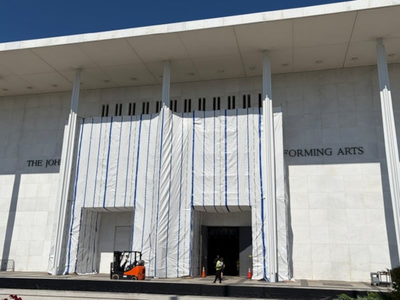 Workers wrap up a move-in through the doors under the scaffolding and tarps that remain covering the Kennedy Center sign on June 17, 2026.