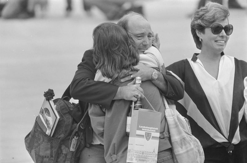 One of the 39 freed American hostages from TWA Flight 847, clutching a bottle of champagne, embraces a relative at Andrews Air Force Base in Maryland, U.S., July 2, 1985. REUTERS/Bill Creighton 85238009