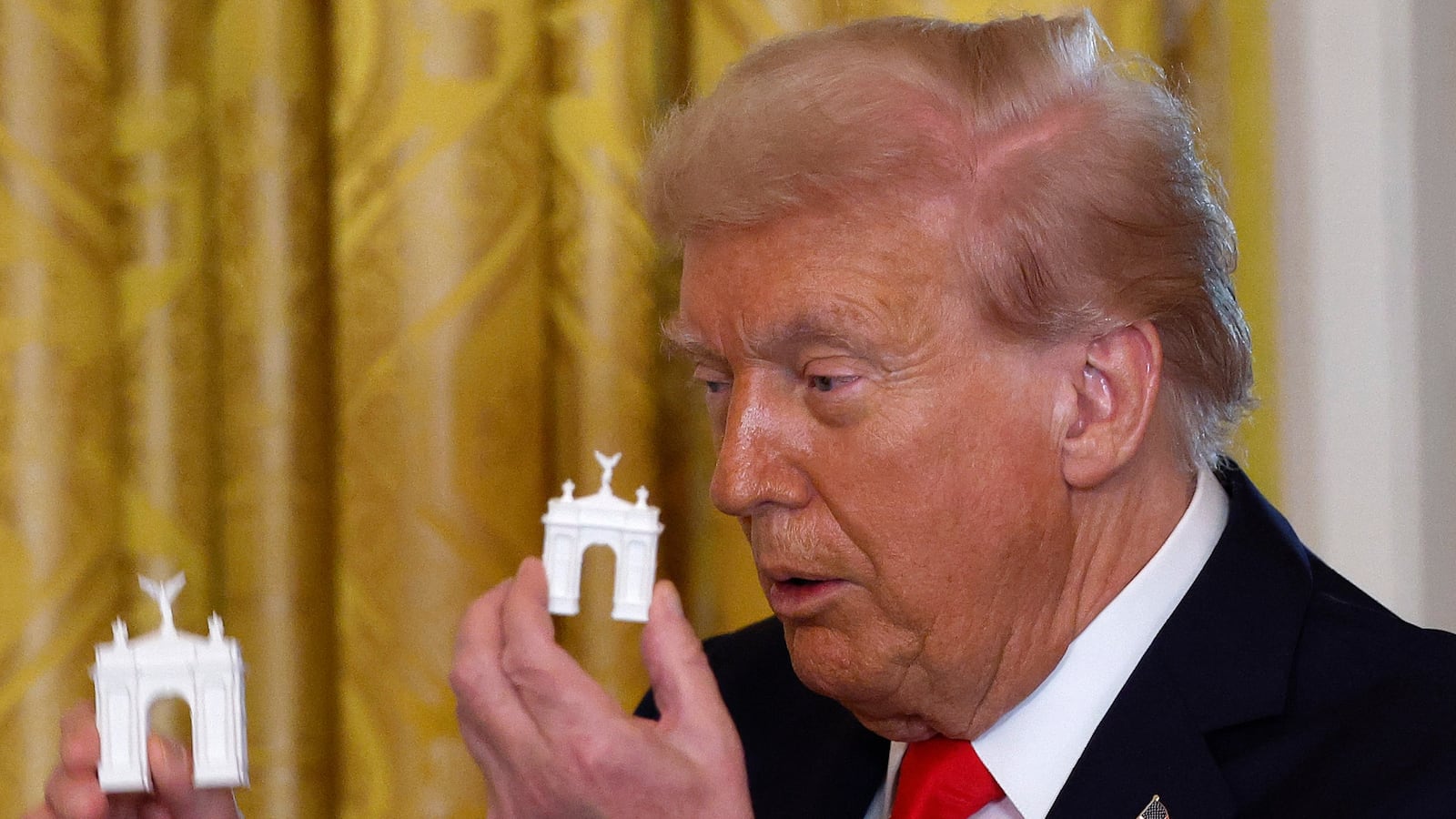 WASHINGTON, DC - OCTOBER 15: U.S. President Donald Trump holds models of an arch as he delivers remarks during a ballroom fundraising dinner in the East Room of the White House on October 15, 2025 in Washington, DC. Trump hosted organizations and individuals for a fundraising dinner for the new $250 million ballroom addition currently under construction at the White House. (Photo by Kevin Dietsch/Getty Images)