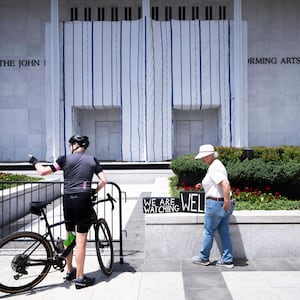 People stand in front of a tarp covering signage on the facade of the Kennedy Center in Washington, DC, on June 15, 2026, after a judge ordered the removal of US President Donald Trump's name from the building.
