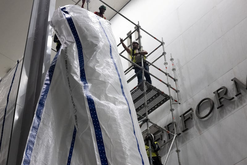 Workers raise a tarp in preparation for the removal of lettering from the facade of the John F. Kennedy Memorial Center for the Performing Arts, following a federal judge’s order to remove U.S. President Donald Trump's name from the institution, in Washington, D.C., U.S., June 13, 2026.