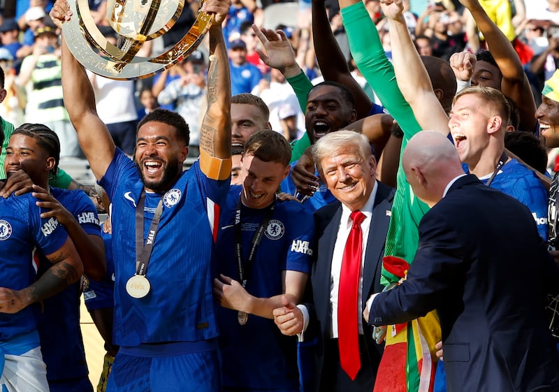 President Donald Trump stays among Chelsea players as captain of Chelsea Reece James lifts the trophy during the ceremony following the FIFA Club World Cup 2025 final football match between Chelsea FC and Paris Saint-Germain (PSG) at MetLife Stadium on July 13, 2025 in East Rutherford, New Jersey.