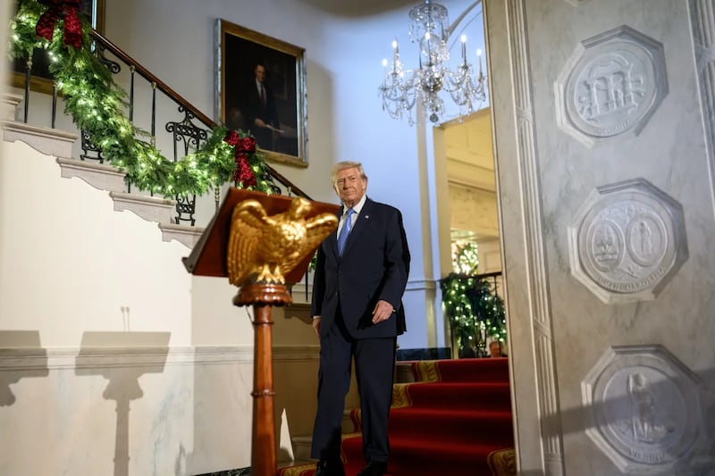 Trump coming down White House stairs to stand behind podium with gold carved eagle on it.