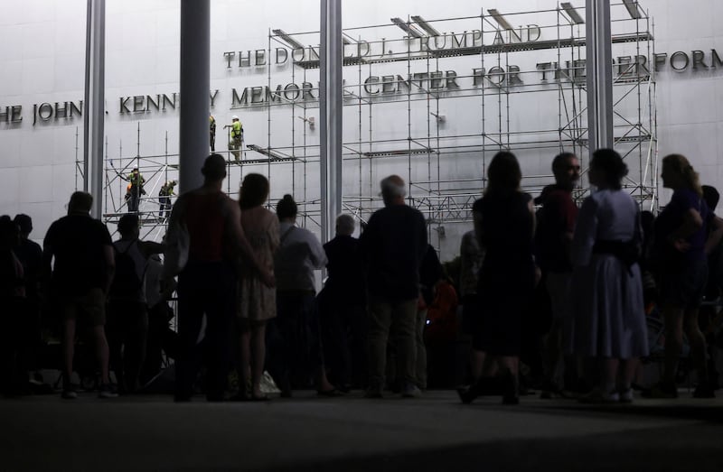 People look at workers as they set up scaffolding to remove lettering from the facade of the John F. Kennedy Memorial Center for the Performing Arts, following a federal judge’s order to remove U.S. President Donald Trump's name from the institution, in Washington, D.C., U.S., June 12, 2026.