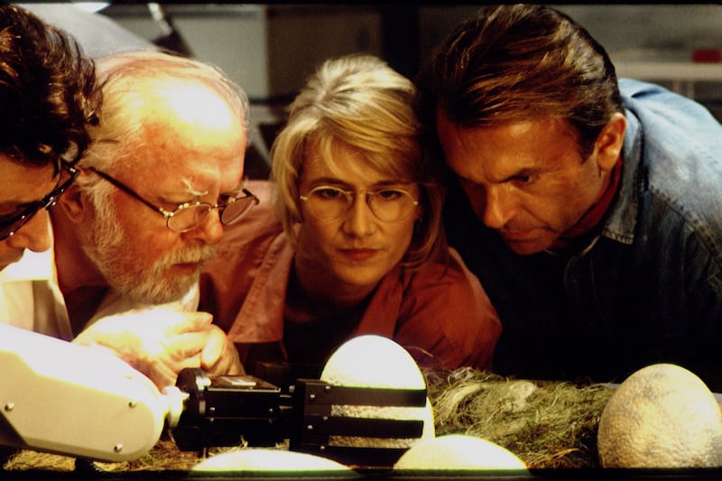 From left to right: Dr. Ian Malcolm (Jeff Goldblum), John Hammond (Richard Attenborough), Dr. Ellie Sattler (Laura Dern), and Dr. Alan Grant (Sam Neill) examine a newly hatched dinosaur egg in the Jurassic Park hatchery.